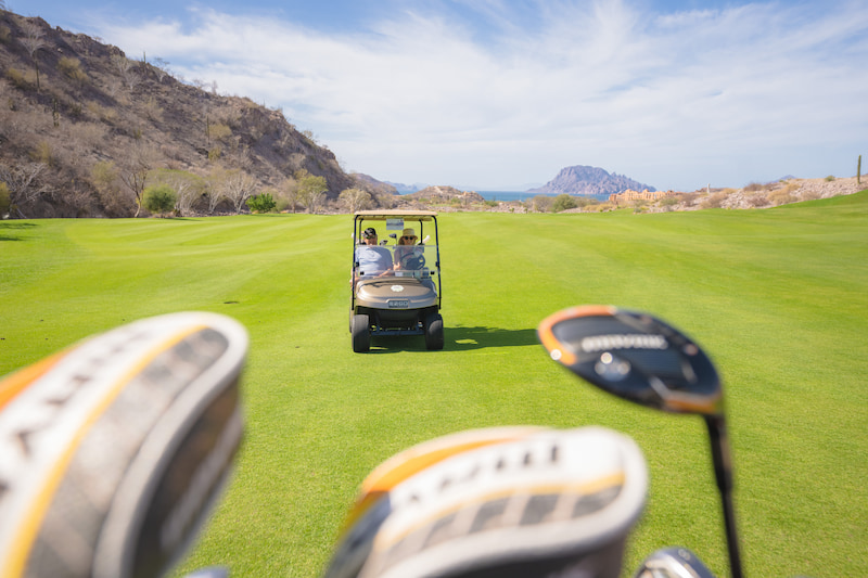 couple driving golf cart at tpc danzante bay in loreto, baja california sur, mexico